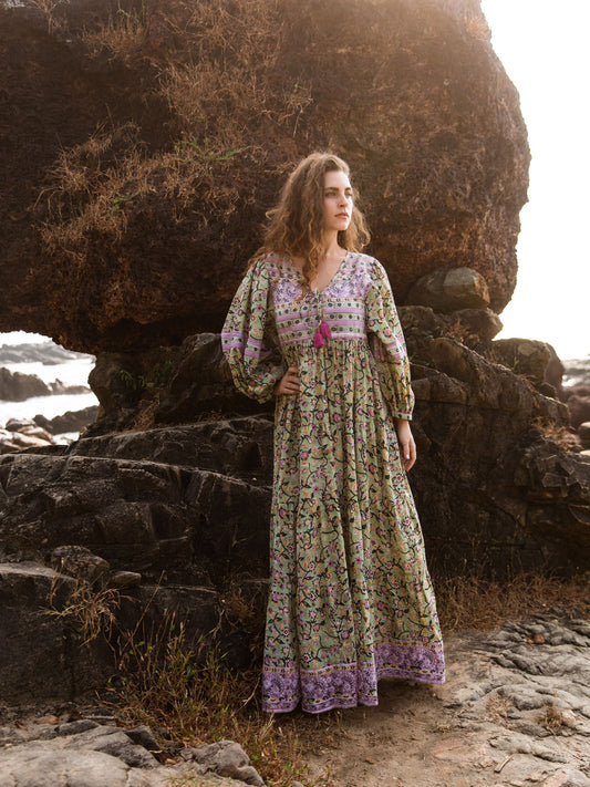 Model in Ubek Bohemian Dress standing by a rocky outcrop on the beach